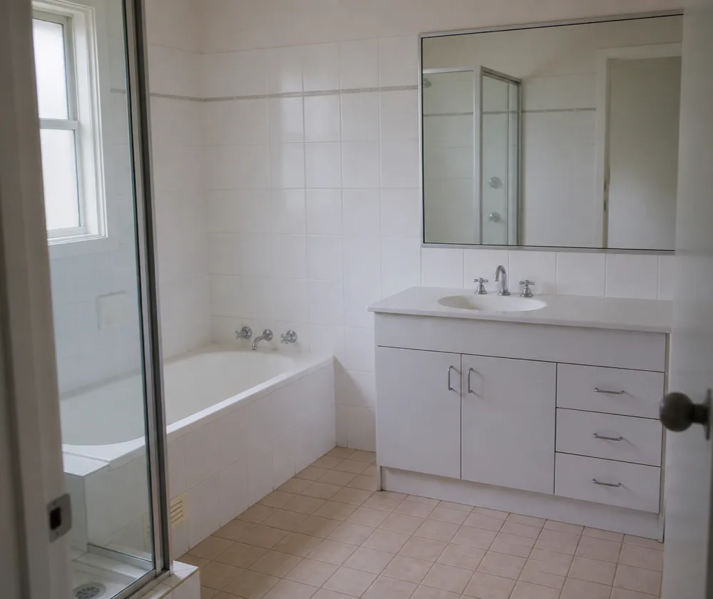 Bond cleaning in Bassendean, empty tiled bathroom with a clean bath, shower screen and vanity