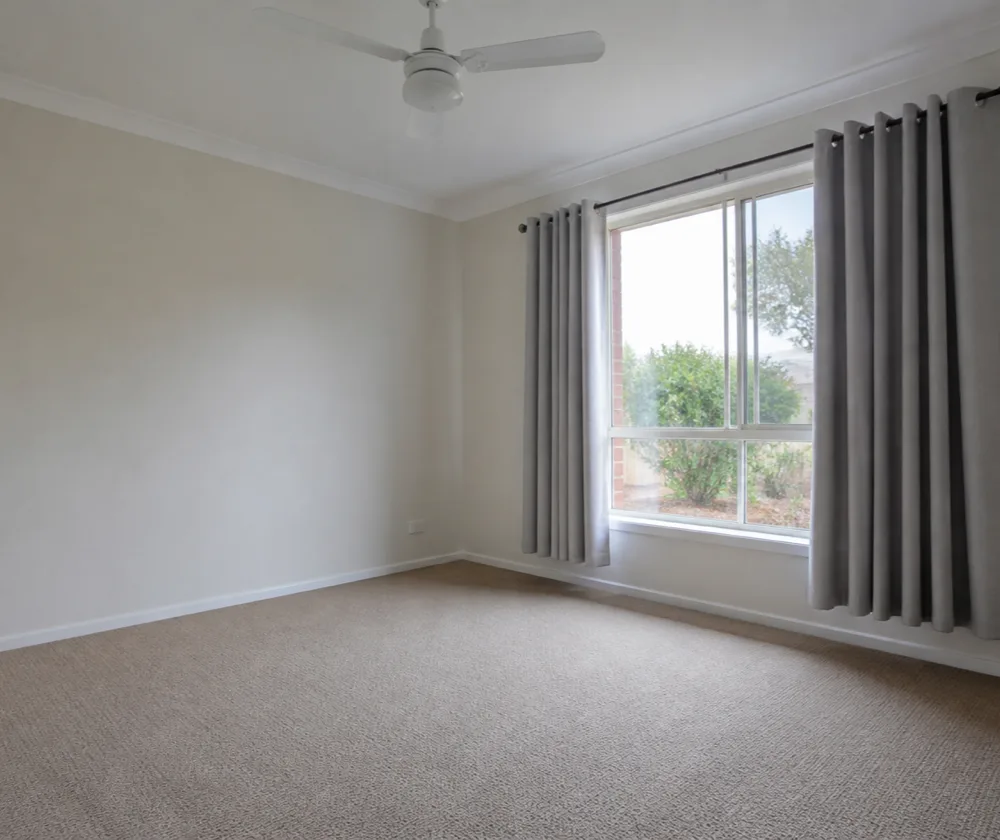Bond cleaning in Cannington, empty carpeted room with a ceiling fan and freshly vacuumed floor