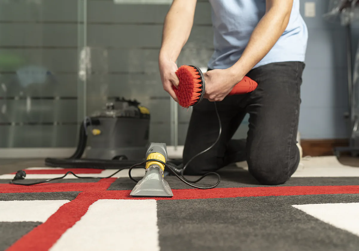 A rotary brush machine being used to deep clean a light coloured rug