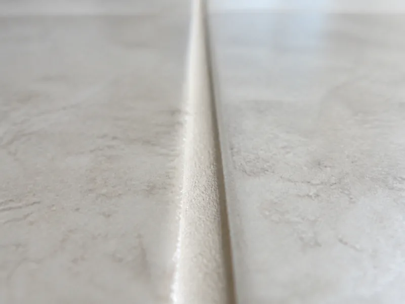 Macro close up of a clean grout channel between two ceramic floor tiles