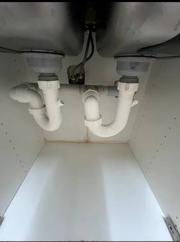 The same under sink cabinet base after cleaning, with the white surface clear of stains and debris